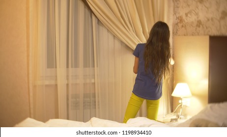 The Girl Shades The Window With A Curtain For The Night