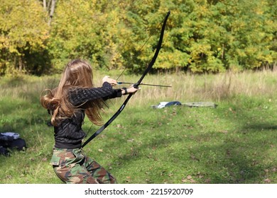 Girl Shooting An Arrow From Longbow In Nature