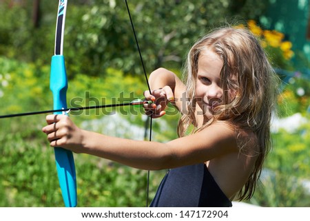 Girl shoots a bow on background of nature