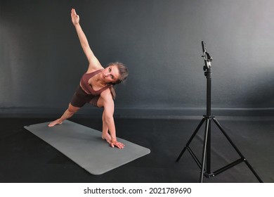 The girl shoots a video of a fitness workout. Online training with a professional yoga coach. Video training remotely on fitness at home. Fitness live. - Powered by Shutterstock