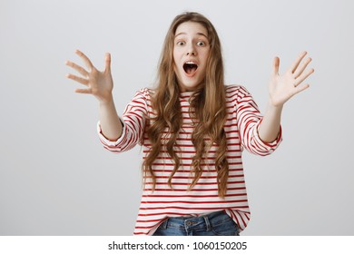 Girl shouting look out to prevent disaster. Nervous and worried attractive woman screaming and pulling palms towards camera to grab friend who is falling from ladder, standing over gray wall