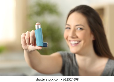 Girl showing an asthma inhaler sitting on a couch in the living room at home - Powered by Shutterstock