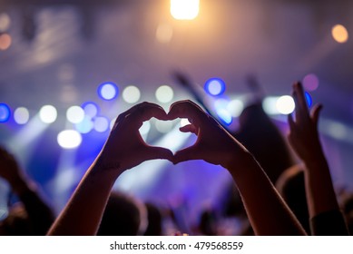 Girl showing heart while partying on a festival.