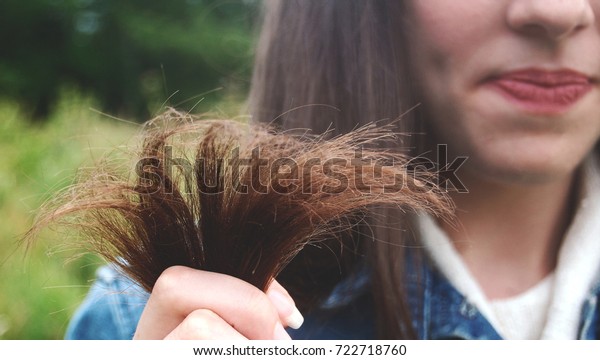 Girl is showing\
her damaged split hair\
ends