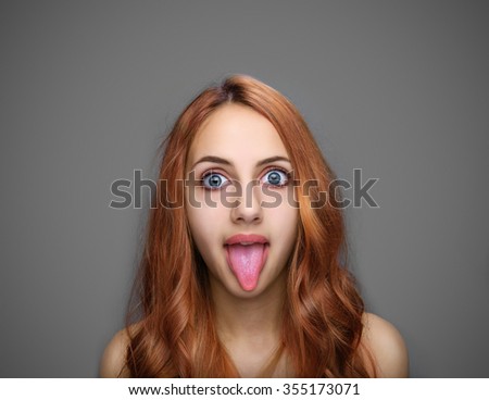 Girl showing tongue isolated on gray.
