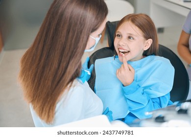 Girl shows her teeth to a woman a dentist - Powered by Shutterstock