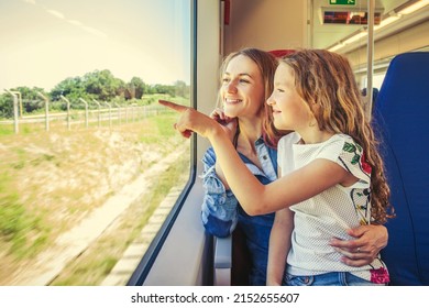 Girl shows his mother something outside the window. Woman with child traveling by pablic transport. Family travelling in a train 