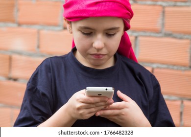 Girl Sick With Cancer And With A Headscarf Using The Mobile Phone