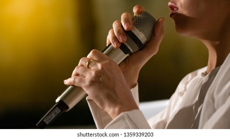 The Girl Is Singing The Song With The Hand Holding The Singing Mic.