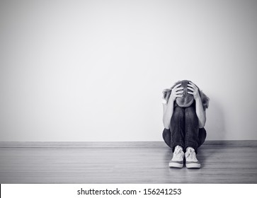 girl sits in a depression on the floor near the wall monochrome