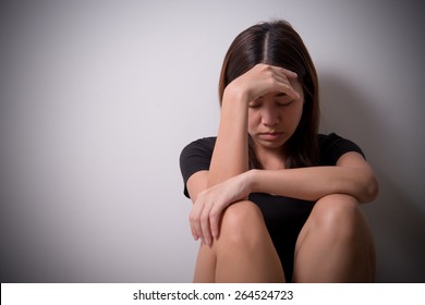 girl sits in a depression on the floor near the wall