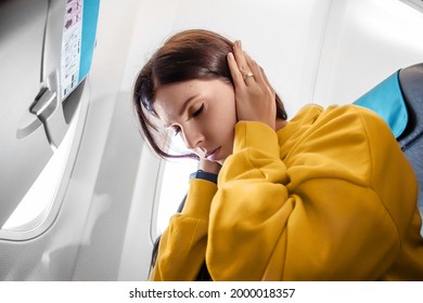 A Girl Sits In Front Of An Airplane Window And Is Nervous, Afraid To Fly, The Cabin Of A Passenger Airliner. Aerophobia, Phobia, International Flights, Stress, Motion Sickness