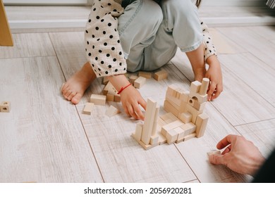 Girl Sits On The Floor In A Room And Plays With Her Dad In A Natral Wood Constructor. Playing With Father. Happy Father's Day. Toys Made Of Eco-friendly Material.
