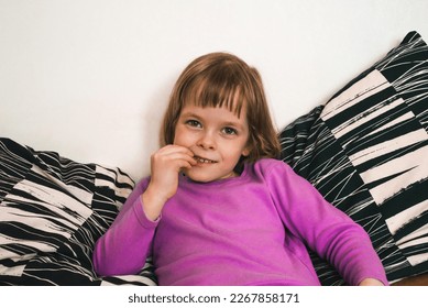 Girl sits on the sofa and eats dried apples
