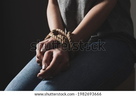 a girl sits tied on a chair in a dark room