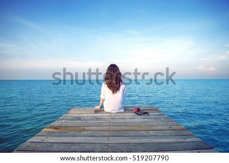 Girl sitting alone on a the wooden bridge on the sea. Vintage tone style. (frustrated depression)