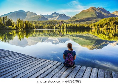 Girl sitting by the lake under mountains- nature photo with copy space. Strbske pleso, Slovakia.
