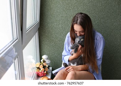 the girl is sitting by the window with a cat - Shutterstock ID 762957637