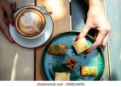 Girl Sitting In Caffe, Drink Coffee And Eat  Tasty Arabic Cookies
