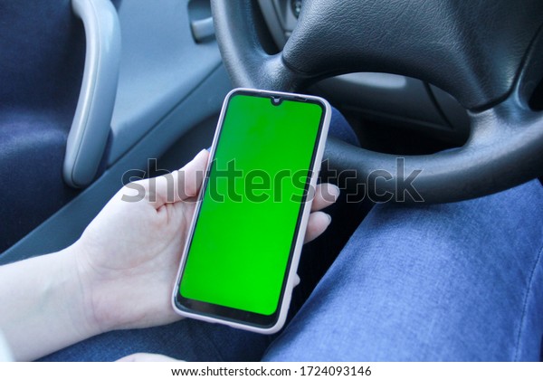 Girl sitting in a\
car and looking at the screen in the phone. Woman holding\
smartphone with empty\
screen.