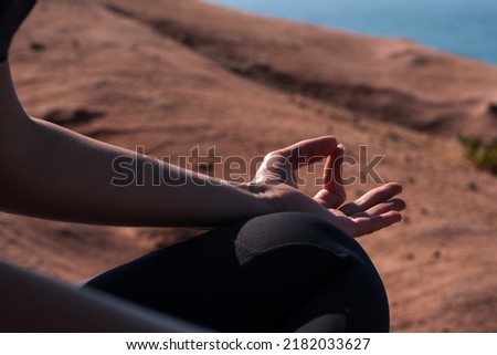 Girl sitting cross-legged at the beach, practicing yoga and enjoying meditation