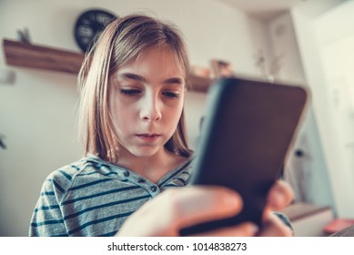 Girl sitting at dining table and using smart phone at home