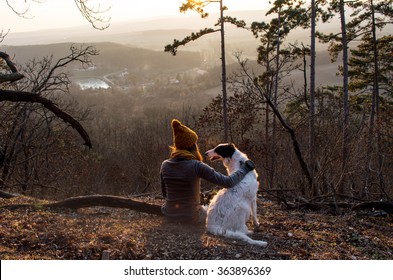 Girl sitting with dog in forest with beautiful view