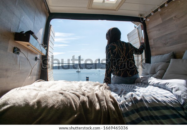 A\
girl sitting in her campervan watching the\
landscape