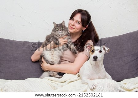 The girl is sitting with her cat and dog