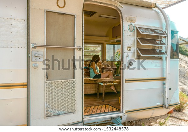 Girl sitting inside a van. White steel\
camper van. Traveler concept. Desert route. \
