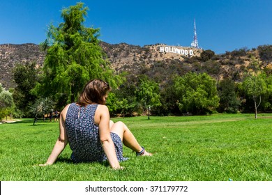 Girl sitting at in the Lake Hollywood Park and the Hollywood sign in the background in Los Angeles