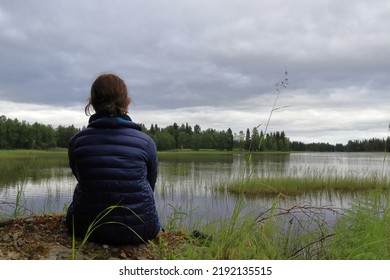 Girl Sitting At A Lake. Watching The View. One Cloudy Swedish Summer Day. Jämtland, Sweden, Europe.