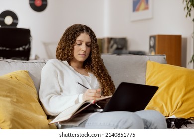 A Girl Sitting In The Living Room On The Couch, Planning Things For The Week, Making A Shopping List, Watching Your Favorite TV Series Via Laptop