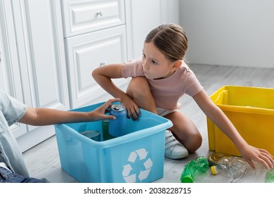 Girl sitting near brother, boxes with trash and recycle sign in kitchen - Powered by Shutterstock