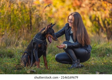 girl sitting near a doberman dog breed in nature