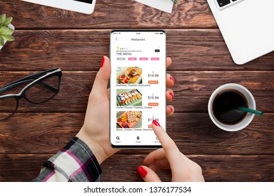 Girl Sitting At The Office Desk And Ordering Food On Her Smartphone With Food Delivery App
