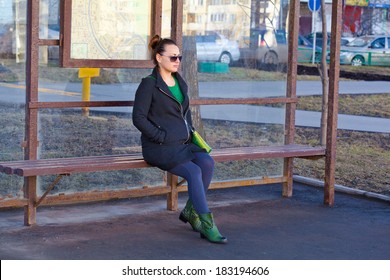 Girl Sitting On A Bench Waiting For Transport At The Bus Stop