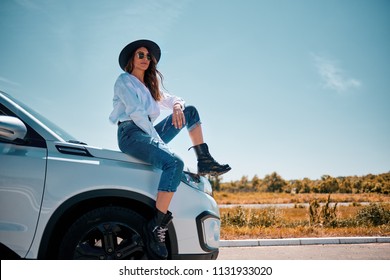 Girl sitting on the car hood. 