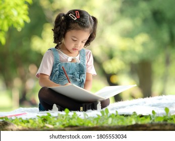 The Girl Sitting On The Carpet, Drawing With Colored Pencils Is Learning Outside Of School To Enjoy Yourself In The Nature Park