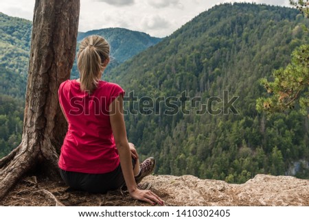 Girl sitting on a cliff looking on the mountains