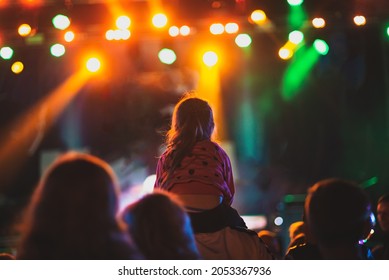 Girl Sitting On Daddy's Shoulders At A Street Concert.