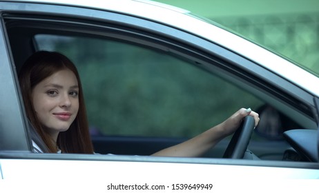 Girl Sitting On Driver Seat In Car Smiling At Camera, Learner Under Instruction