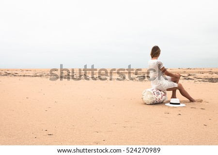 Girl sitting on a fishing buoy on the sandy coast of the sea.