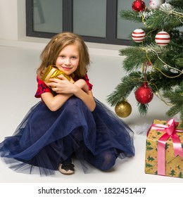 Girl Sitting On Floor Next Decorated Xmas Tree Hugging Gift Box