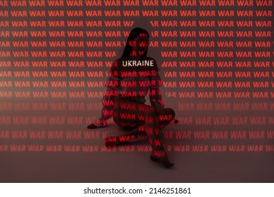 Girl sitting on the floor in the studio under the projector light. Many words glow red. Ukraine and the war. Support and pray for Ukraine. Stop the war.