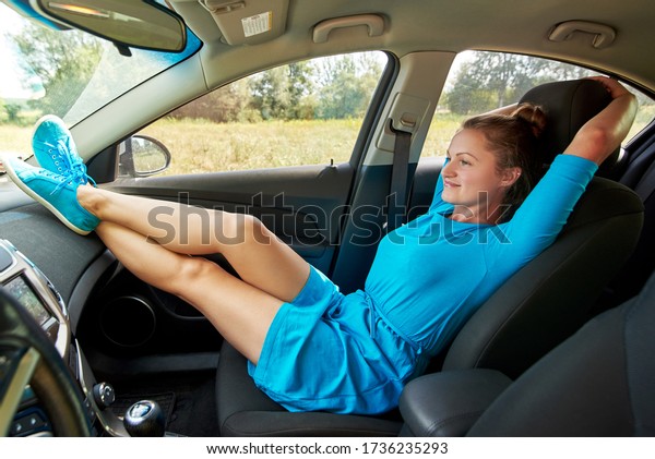 Girl sitting on passenger seat in car with feet\
on car dashboard. Young woman relaxing in car. Freedom, travel\
concept. Spending weekend in\
roadtrip