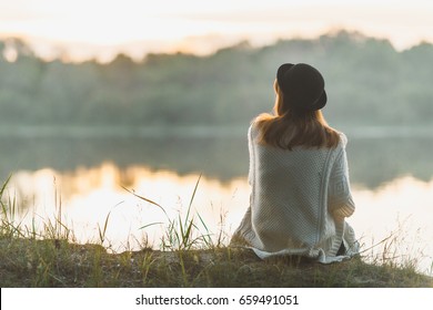 A girl sitting on the river bank in silence