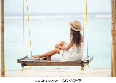 Girl sitting on a swing looking at the ocean