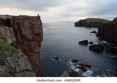 Girl sitting on the top of the cliff enjoying beautiful view