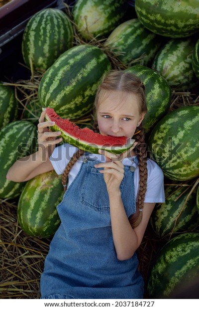 The girl is sitting on watermelons\
in the car. Eating a watermelon. Summer. Autumn. Harvesting.\
Environmentally friendly products. Agriculture.\
Farming.
